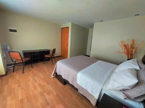 um quarto com uma cama, uma secretária e cadeiras em Casa Mahulu em Paracas
