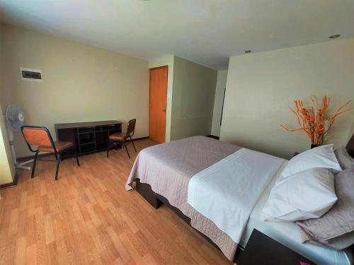 Un dormitorio con una cama y un escritorio y sillas. en Casa Mahulu, en Paracas
