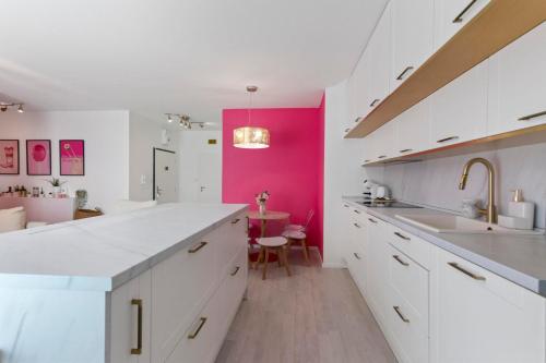 a kitchen with white cabinets and a pink accent wall at LAM Pink with Jacuzzi & PS4 in Bratislava