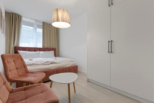 a bedroom with a bed and a chair and a table at LAM Pink with Jacuzzi & PS4 in Bratislava