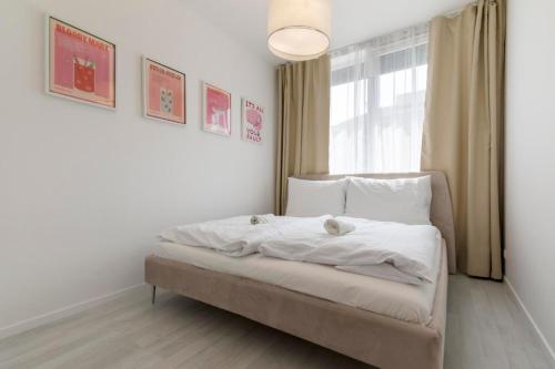 a bedroom with a bed with white sheets and a window at LAM Pink - JACUZZI - AC - PS4 in Bratislava