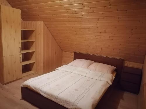 a small bedroom with a bed in a wooden room at Domek Smerfna Chatka in Wąglikowice