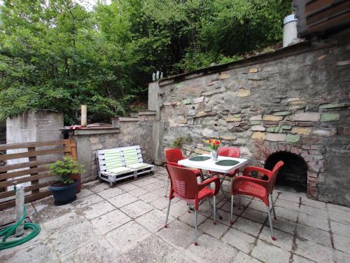 a patio with a table and chairs and a stone wall at Happy Holidays in Borjomi