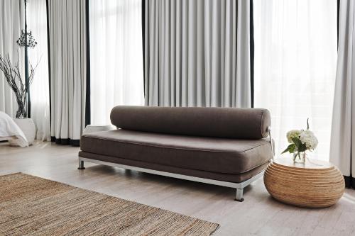 a brown couch in a living room with curtains at Bungalow Hotel in Long Branch