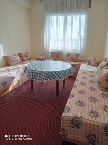 um quarto com duas camas e uma mesa em Grand appartement à deux pas de la plage em Souira Guedima
