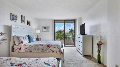 a white bedroom with two beds and a television at 6415 Midnight Pass #307 in Siesta Key