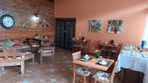 um restaurante com mesas e cadeiras e um relógio na parede em Pousada Estrelícia em Cunha