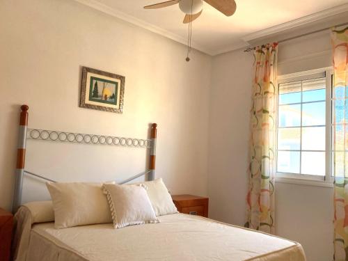Un dormitorio con una cama con ventilador de techo y una ventana. en Dúplex Bahía Terreros, en San Juan de los Terreros
