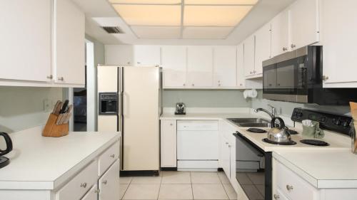 een witte keuken met witte kasten en een koelkast bij 6415 Midnight Pass #409 in Siesta Key