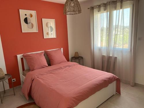 een slaapkamer met een bed met rode muren en een raam bij vacances en Ardéche "maison Chauvet" in Vallon-Pont-dʼArc