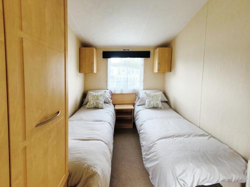 a small room with two beds and a window at Kingfisher Corner in South Cerney