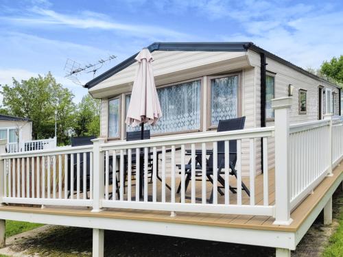 a tiny house with a deck and an umbrella at Kingfisher Corner in South Cerney
