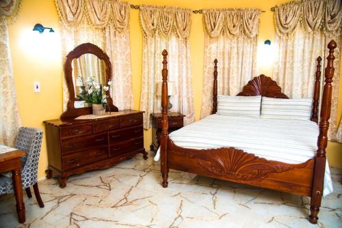 a bedroom with a bed and a dresser and a mirror at Dela de-Rose Guest House Negril Jamaica in Negril