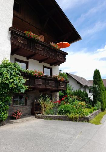 un edificio con balcón con flores y sombrilla en Haus Pyhrgasblick, en Windischgarsten