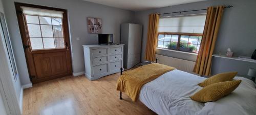 a bedroom with a bed and a dresser and two windows at The Madden Guest House in Gilford