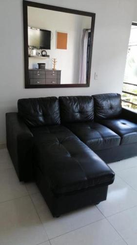 a black leather couch in a living room with a mirror at SANTYS HOUSE MELGAR apartamentos amoblados con capacidad para 6 personas para 6 personas in Melgar