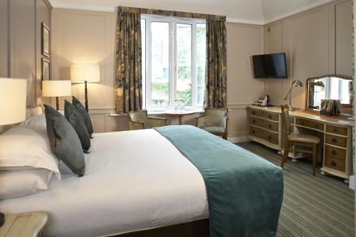 a hotel room with a large bed and a desk at Sir Christopher Wren Hotel in Windsor