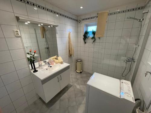 y baño blanco con lavabo y ducha. en Kjerkgata 6 - midt i Røros sentrum, en Røros