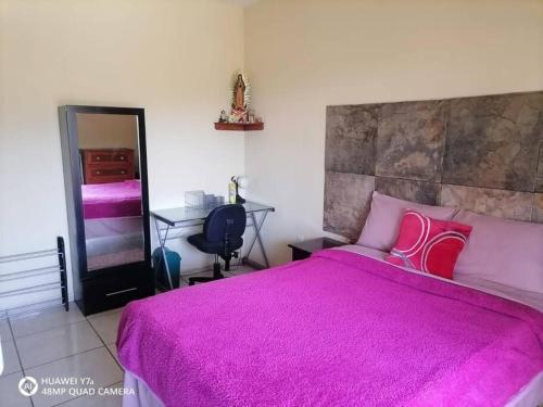 um quarto com uma grande cama rosa e uma secretária em Casa Noria em Tepic