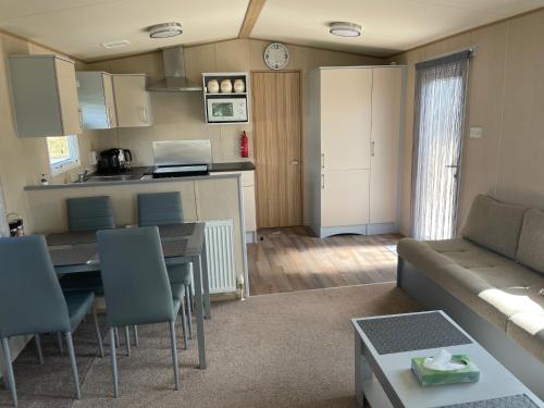a living room with a couch and a table and a kitchen at Summer Breeze-Hoburne Cotswolds in South Cerney