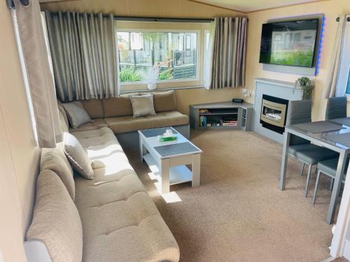a living room with a couch and a table at Summer Breeze-Hoburne Cotswolds in South Cerney