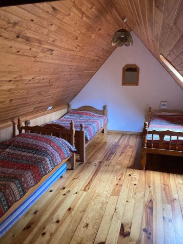 Cette chambre mansardée dispose de deux lits et de parquet. dans l'établissement Rustikales Haus im Naturparadies, à Saint-Étienne-de-Tinée