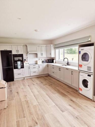 a large kitchen with white cabinets and white appliances at Buncrana Beach House by Wild Atlantic Wanderer in Buncrana