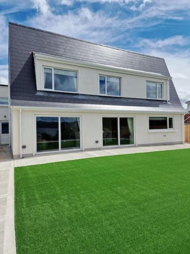 a house with a green lawn in front of it at Buncrana Beach House by Wild Atlantic Wanderer in Buncrana