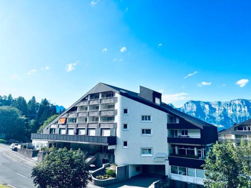 an apartment building with mountains in the background at Gauencenter EG - CharmingStay in Flums