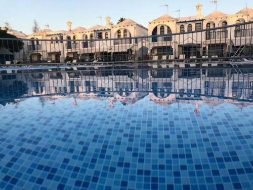 a pool with blue tiles in front of a building at Bungalow Maspalomas in Maspalomas