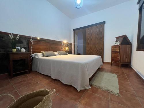 a bedroom with a large white bed and a chair at CASA CANARIA ACERÓ in Garachico