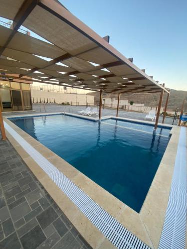 a swimming pool with awning and blue water at Jarash farm in Jerash