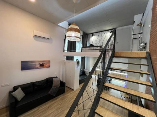 a living room with a black couch and a staircase at Carbonell 1 in Valencia