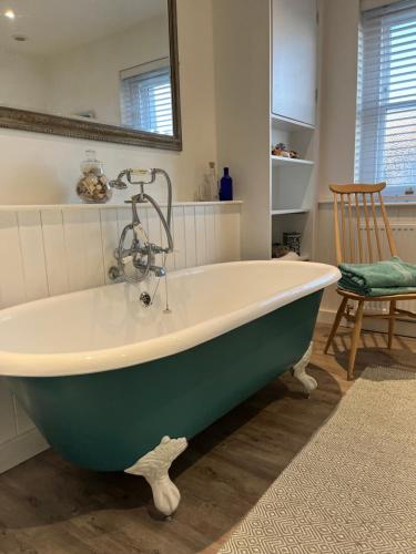 y baño con bañera verde y blanca. en Billie's seaside retreat, en Lyme Regis