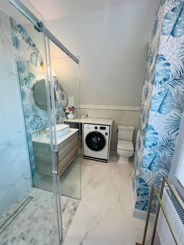 a bathroom with a shower and a washing machine at Apartament pod Kasztanem in Lębork