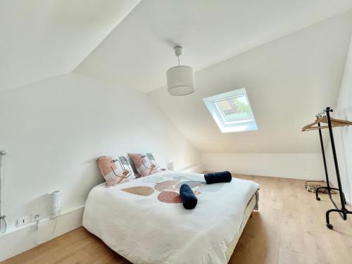 a bedroom with a bed with white sheets and a skylight at LE FOUR A PAIN - Campagne entre Plages et Quimper in Pluguffan