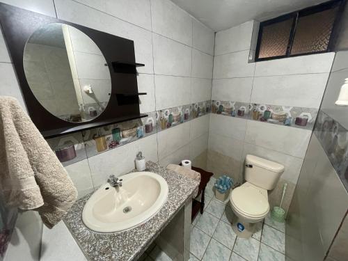 een badkamer met een wastafel, een toilet en een spiegel bij Hermoso departamento en el corazón de Papallacta in Papallacta