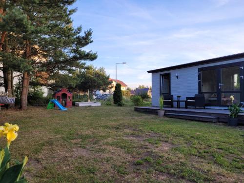 a tiny house in a yard with a playground at "AGUŚ" Komfortowe i nowczesne domki w cichej okolicy niedaleko plaży in Ostrowo