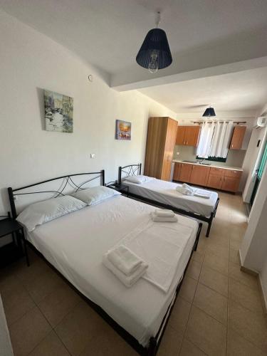 two twin beds in a room with a kitchen at lazari Rooms in Himare