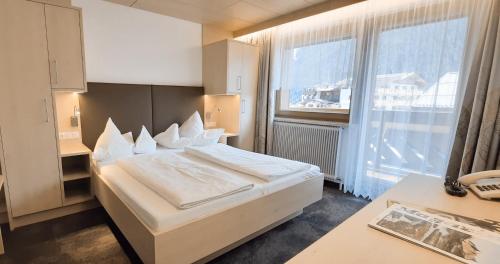ein Schlafzimmer mit einem Bett und einem großen Fenster in der Unterkunft Frühstückspension Rehwinkl in Sölden