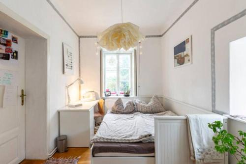 a small bedroom with a bed and a chandelier at MARONA - Home Studio - where Music and Art meet Business in Perchtoldsdorf