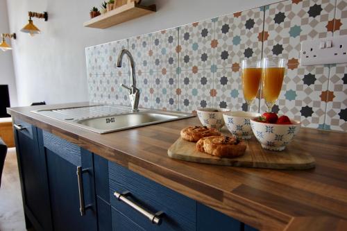 una barra de cocina con dos tazones de comida y dos vasos de zumo en Farways Den, en Haworth