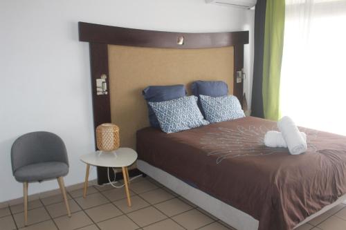 a bedroom with a bed and a chair at Régent 3e étage Papeete in Papeete