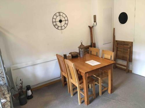 une table à manger avec des chaises et une horloge murale dans l'établissement Logement au pied des pistes Superdevoluy, à Saint-Étienne-en-Dévoluy