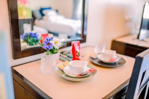 stół z dwoma kubkami i wazon z kwiatami w obiekcie TYCOON PLACE Garden 泰坤华裔酒店 w Pattaya South