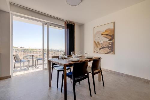 a dining room with a table and chairs and a large window at Valley's Edge Apartments in San Ġwann