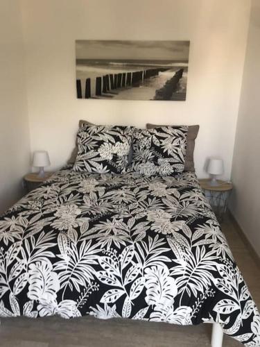 une chambre avec un lit avec une couette noire et blanche dans l'établissement Location saisonnière 2 p Antibes-Piscine-Climatisation-terrasse au calme, à Antibes