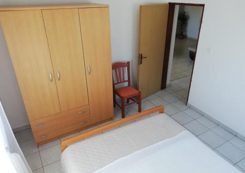 a room with a chair and a cabinet and a mirror at Apartman Mrgic in Preko