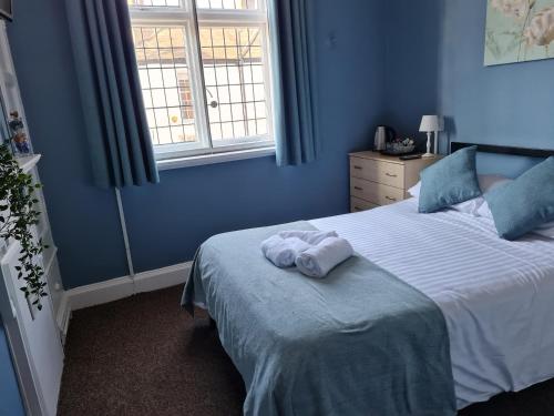 a blue bedroom with a bed with towels on it at The Saddle Inn in York