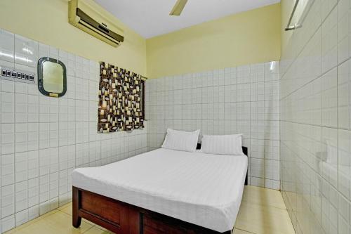 a small room with a bed and a shower at OYO 86379 Dream Palace Guest House Near Marina Beach in Chennai